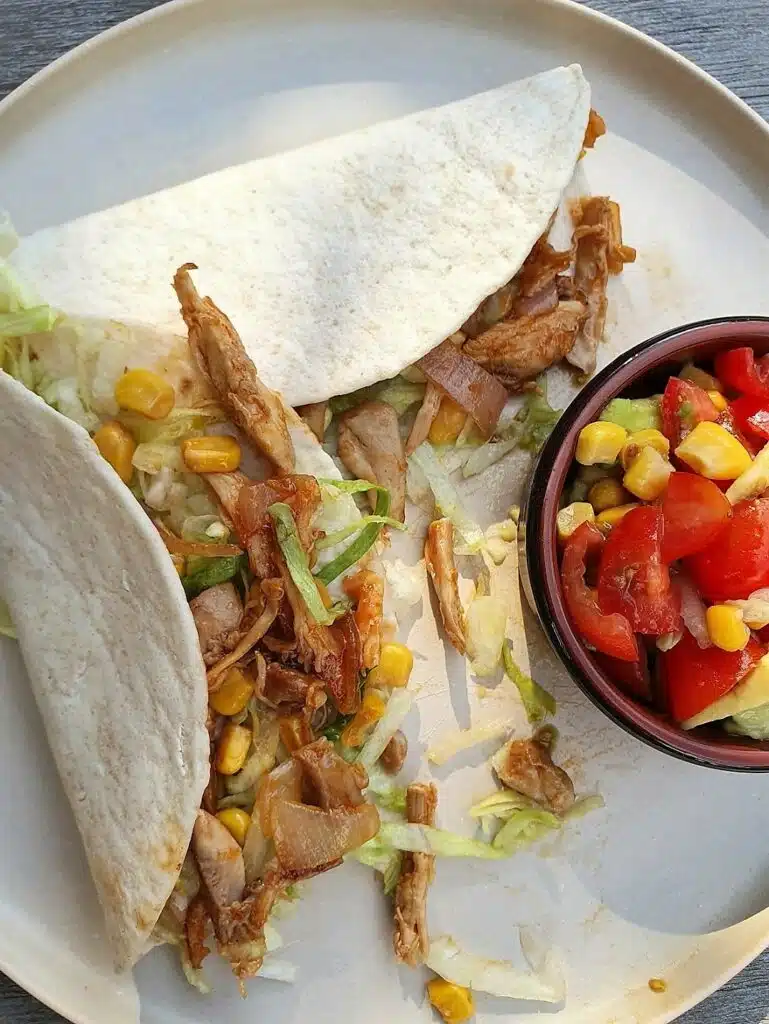 bord met een tortilla met pulled chicken en bakje tomatensalsa