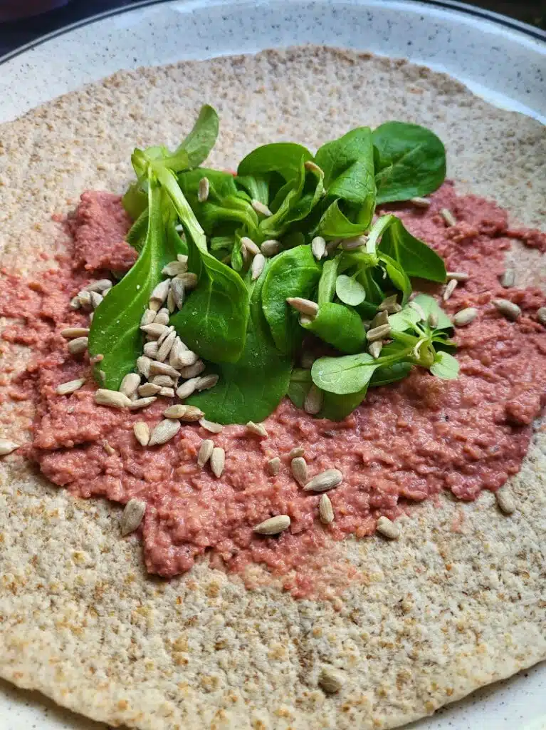 wrap belegd met bietenhummus, sla en pitjes 